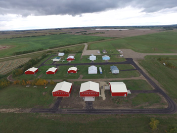 Aerial shot of white roofed and red walled buildings in gree field