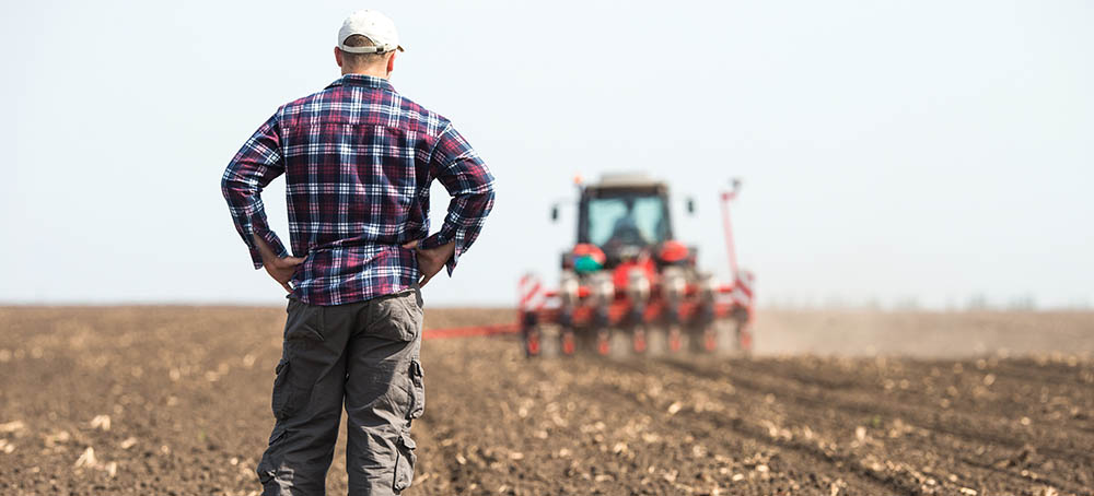  young farmer on farmland with tractor in background