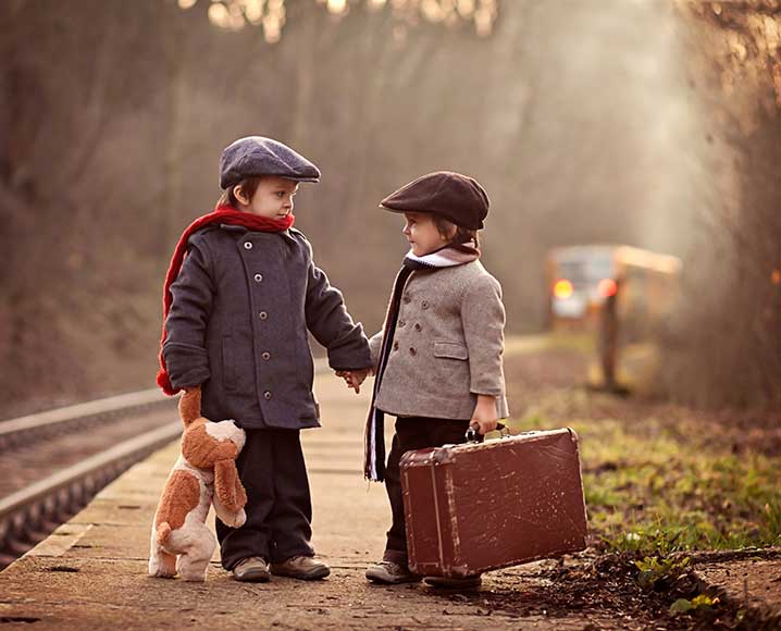 Two young boys dressed in warm clothing holding hands