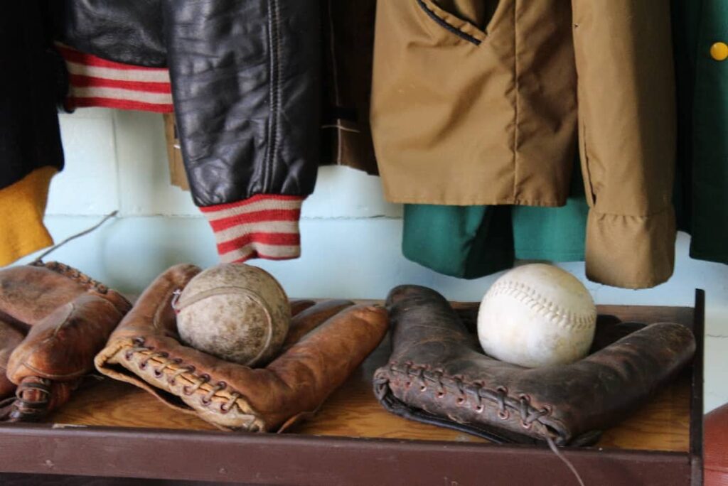 Baseball gloves and white balls sitting on bench